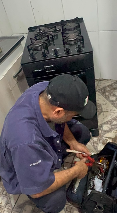 Técnico da Perluiz consertando fogão em cozinha residencial